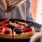 a person pouring syrup on a plate of food