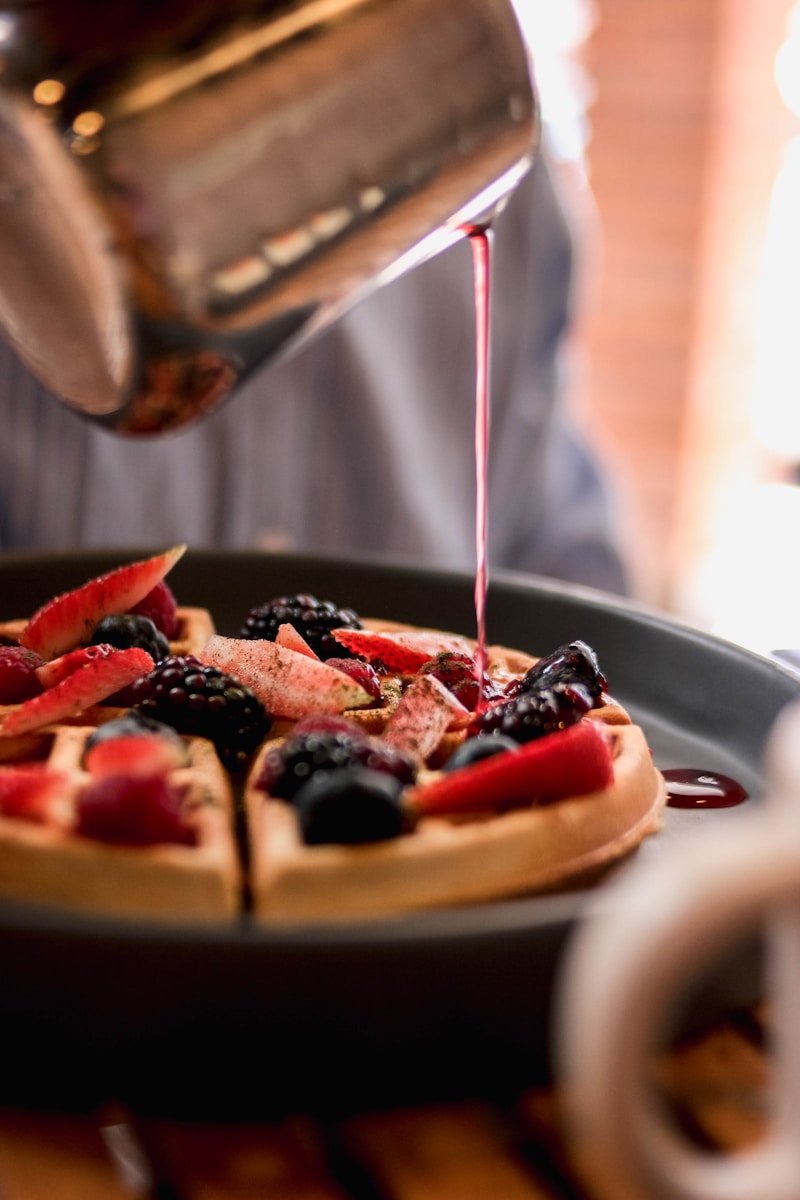 a person pouring syrup on a plate of food