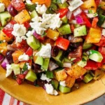 Colorful chopped salad prepared with a spoon, featuring fresh vegetables and herbs.