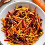 Fresh and colorful carrot salad served in a bowl, garnished with herbs.