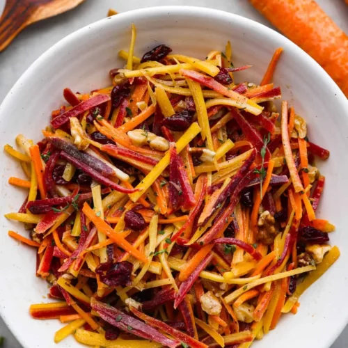 Fresh and colorful carrot salad served in a bowl, garnished with herbs.