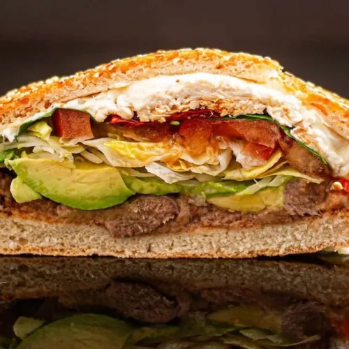A delicious cemita sandwich featuring meat, avocado, and fresh ingredients.