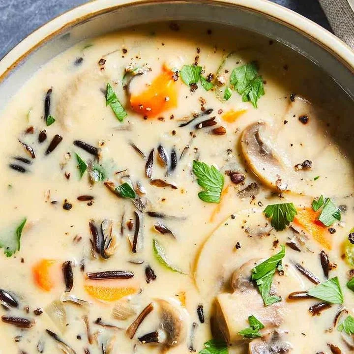 Creamy wild rice soup with mushrooms, garnished for a hearty meal.