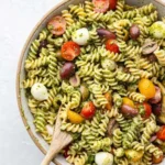 Fresh pesto pasta salad with vegetables and herbs in a bowl