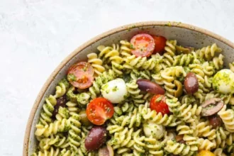 Fresh pesto pasta salad with vegetables and herbs in a bowl