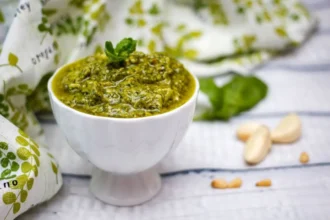Homemade pesto sauce with fresh basil and pine nuts in a bowl.
