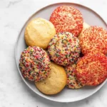 Batch of soft sugar cookies on a plate with festive decorations.