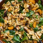 Delicious teriyaki spinach pasta salad in a bowl, topped with colorful vegetables.