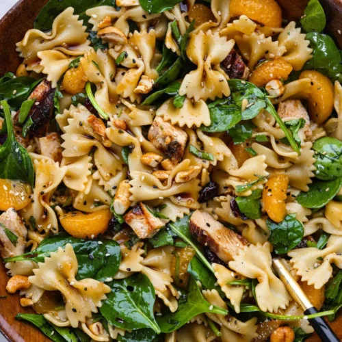 Delicious teriyaki spinach pasta salad in a bowl, topped with colorful vegetables.