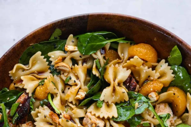 Delicious teriyaki spinach pasta salad in a bowl, topped with colorful vegetables.