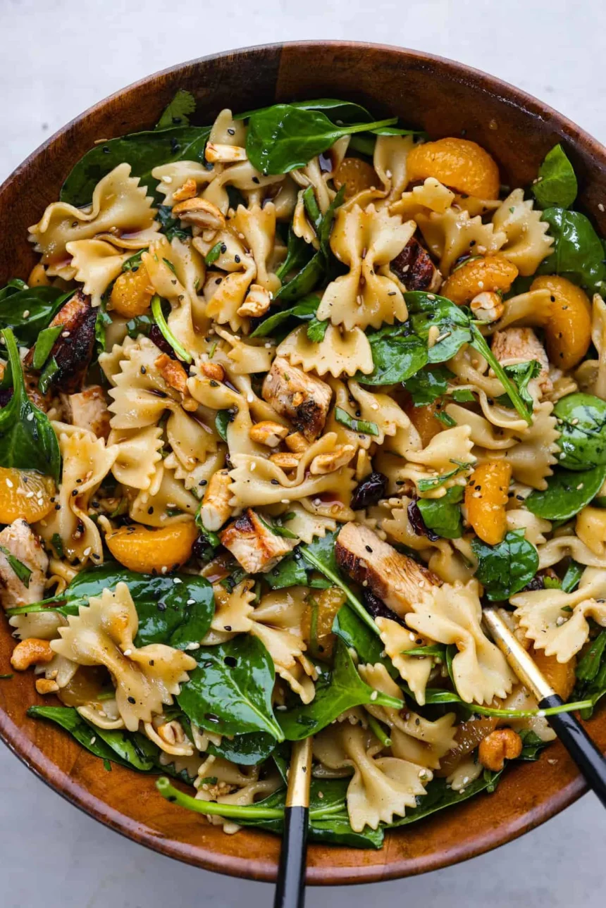 Delicious teriyaki spinach pasta salad in a bowl, topped with colorful vegetables.