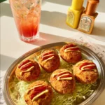 Crispy potato croquettes served on a plate, garnished with fresh herbs.