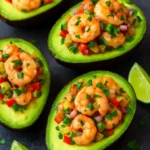 Shrimp-stuffed avocados served on a plate, garnished with lime and cilantro
