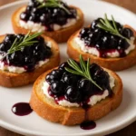 Tangy whipped goat cheese crostini drizzled with blueberry balsamic glaze.
