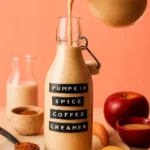 Dairy-free pumpkin spice coffee creamer in a bottle with coffee cup.