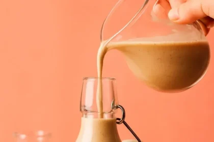 Dairy-free pumpkin spice coffee creamer in a bottle with coffee cup.