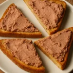 Liver pâté spread on hot buttered toast, topped with herbs.