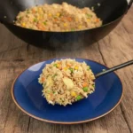 Plate of easy chicken fried rice garnished with green onions and vegetables.