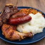 South African barbecue plate featuring pap, grilled steak, and sausage
