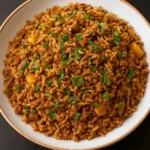A bowl of Vegan Cajun Dirty Rice topped with fresh herbs and spices.