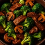 Beef stir-fry with broccoli and mushrooms in a skillet.