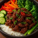 Delicious crispy beef rice bowl topped with fresh vegetables and sauce