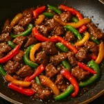 Plate of crispy Hunan beef garnished with vegetables and spices.