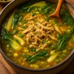 Bowl of Ginger Chicken Soup with bok choy and rice, garnished with green onions.