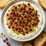 Pomegranate Pistachio Whipped Feta dip served in a bowl with a sprinkle of nuts.